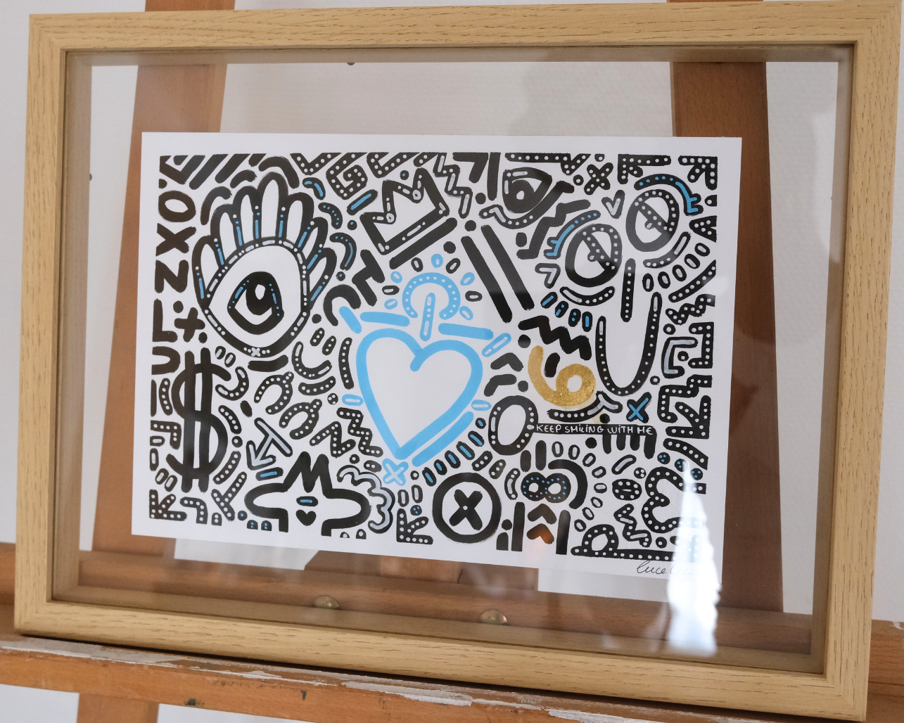 Dessin A4 encadré de la série Keep Smiling With Me n°14, composition noire avec détail bleu ciel et feuille d’or.